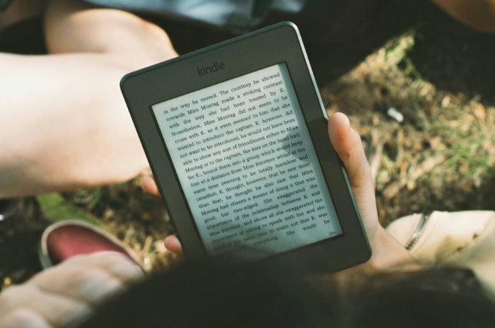 Person holding a Kindle e reader while outdoors