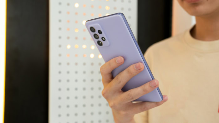 Person holding a purple Samsung smartphone against a pegboard