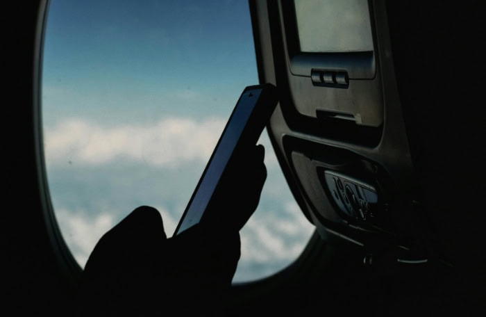 Person holding a smartphone near airplane window