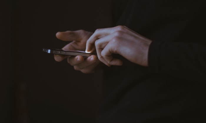 Person holding a smartphone on a dark background