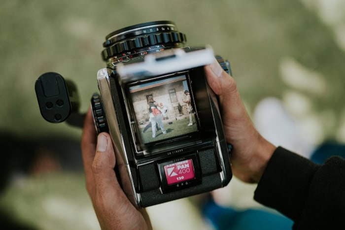 Person holding a vintage camera capturing an outdoor scene