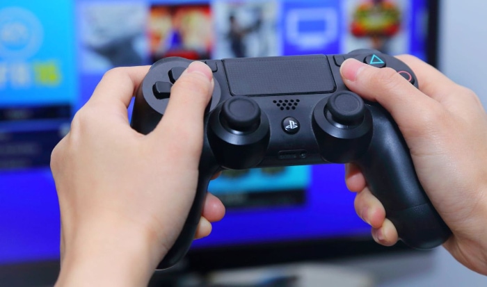 Person holding black PS4 controller