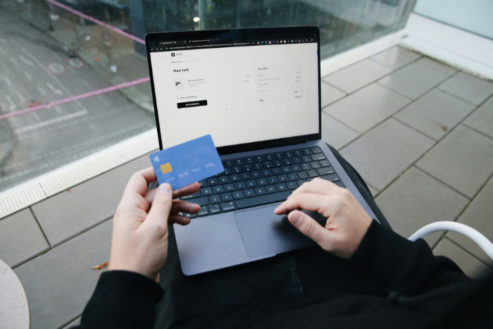 Person holding blue debit card near laptop checkout
