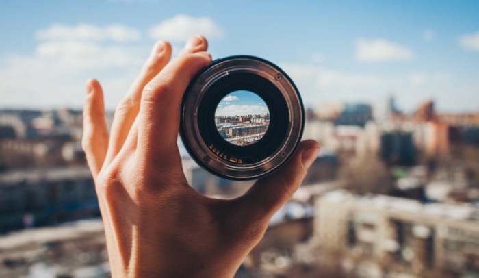 Person holding camera lens