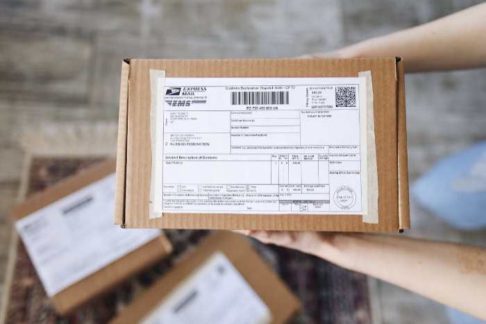 Person holding cardboard shipping box with customs label