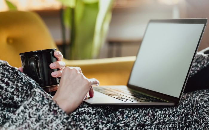 Person holding coffee mug while using laptop