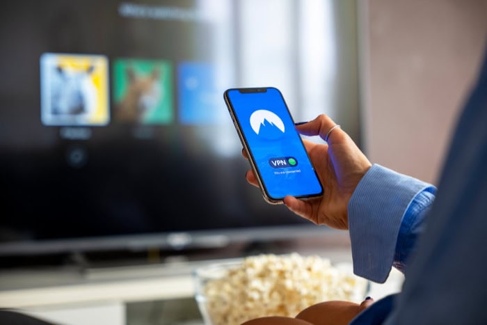 Person holding phone with VPN app near TV