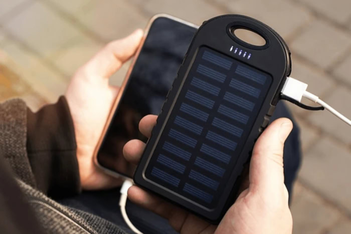 Person holding solar power bank charging mobile phone