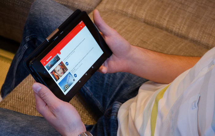 Person holding tablet displaying YouTube app interface