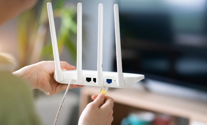 Person holding white wireless router with four antennas
