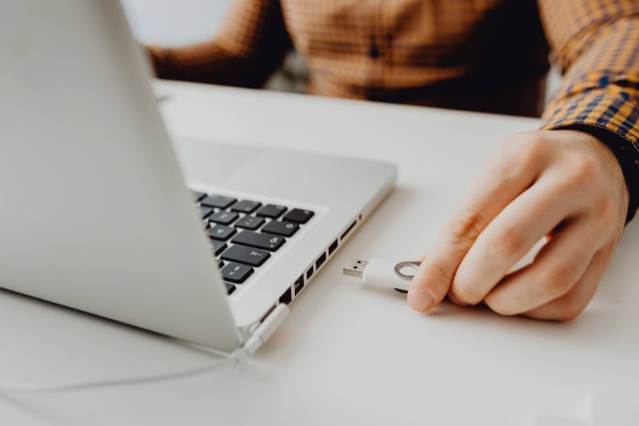 Person inserting a USB flash drive into a laptop