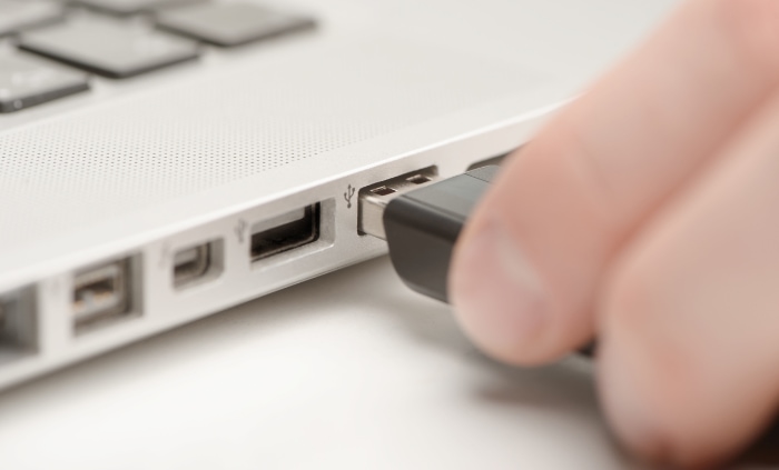 Person inserting a USB flash drive into a laptops USB port