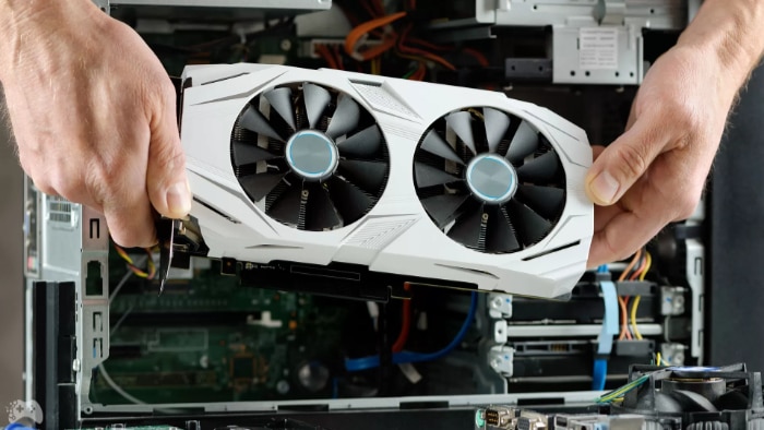 Person installing a white dual fan graphics card into a desktop computers motherboard