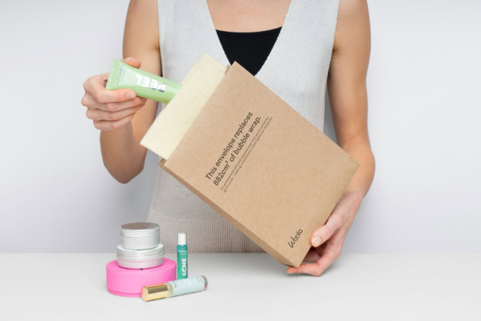 Person packing cosmetics in sustainable paper envelope