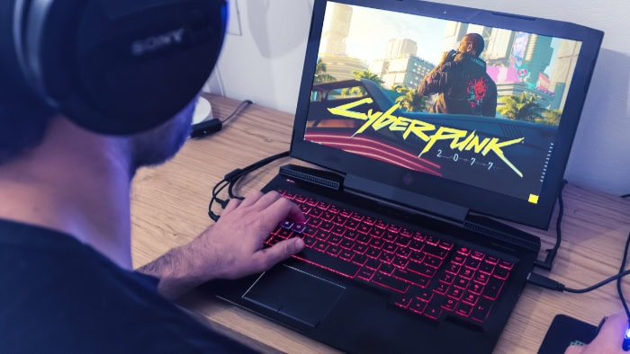 Person playing Cyberpunk 2077 on a gaming laptop