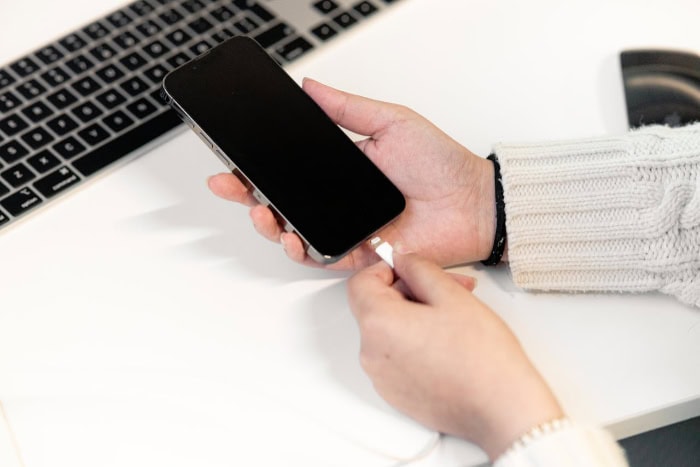 Person plugging charging cable into smartphone 1