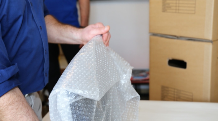 Person preparing bubble wrap for packing a monitor