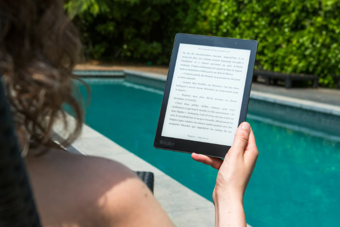 Person reading a Kobo e reader by a pool