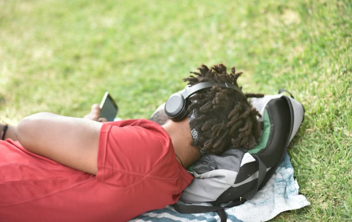 Person relaxing on grass wearing wireless headphones