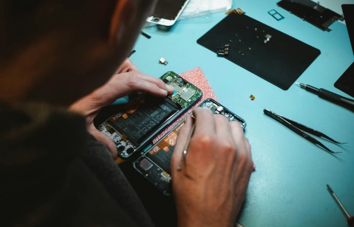 Person repairing smartphone on blue workspace