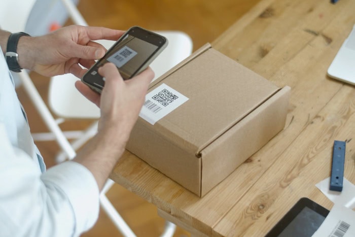 Person scanning QR code on package with smartphone