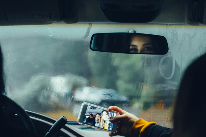 Person taking a Snapchat selfie with friends inside car