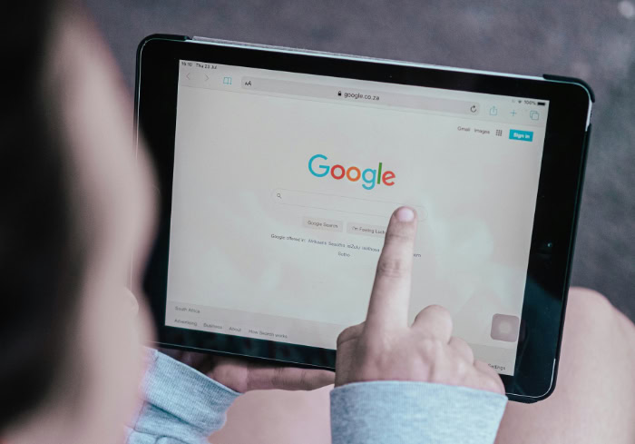 Person tapping Google search on tablet device