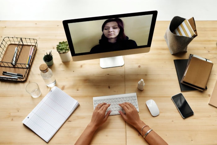 Person typing during a video call on a desktop computer