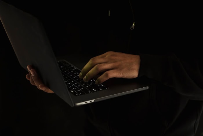 Person typing on a laptop in a dark room