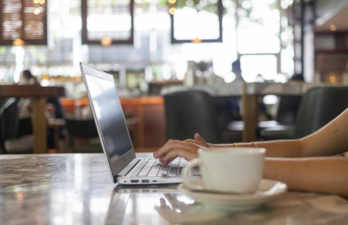 Person typing on a laptop with coffee on the table