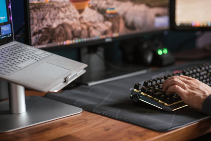 Person typing on a mechanical keyboard near a laptop