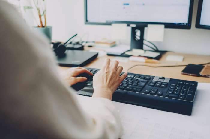 Person typing on black computer keyboard at desk resized