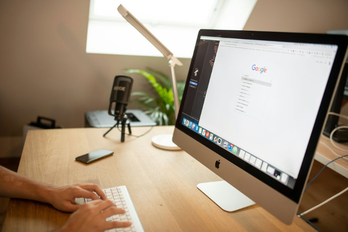 Person typing on keyboard in front of iMac resized