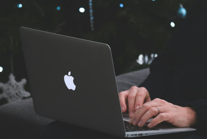 Person typing on laptop against dark background