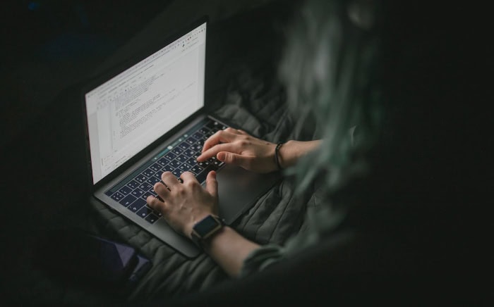 Person typing on laptop in dark room