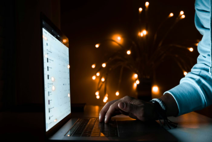 Person typing on laptop keyboard with warm ambient lights