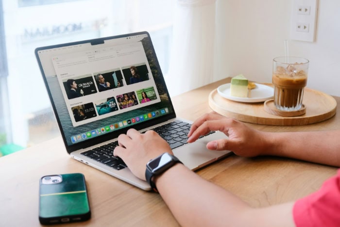 Person using MacBook Air with coffee and dessert nearby