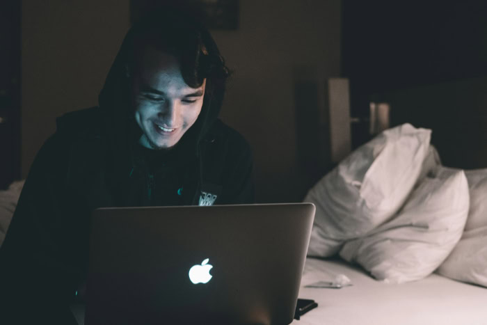 Person using MacBook laptop in dark room