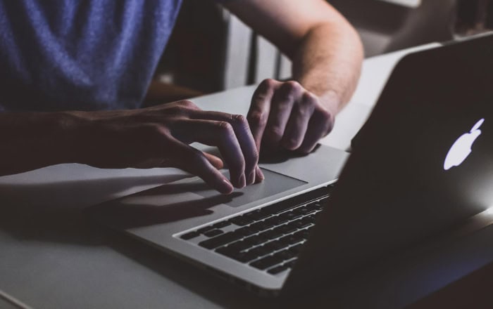 Person using MacBook laptop in dimly lit room