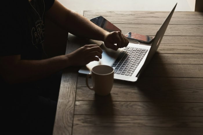 Person using a laptop with coffee mug nearby