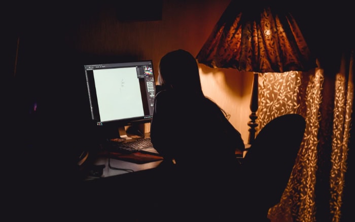 Person using computer at night with decorative lamp nearby