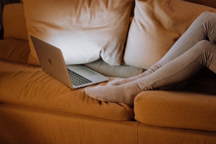 Person using laptop on couch in dimly lit room