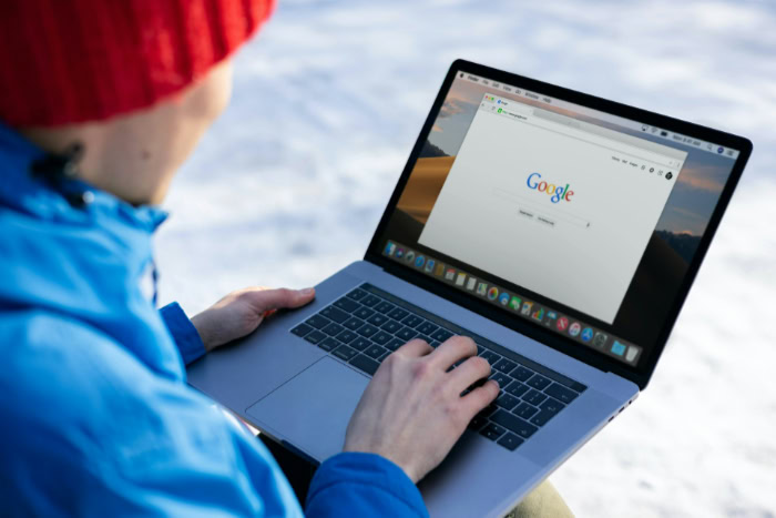 Person using laptop outdoors in winter clothing