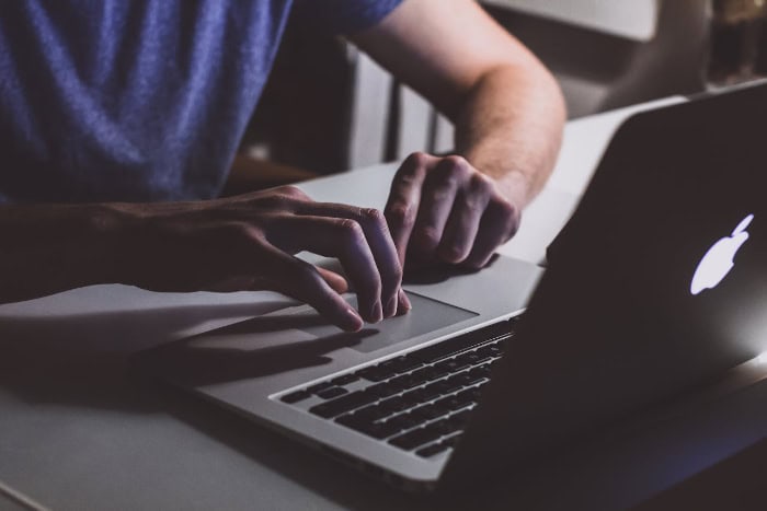 Person using laptop touchpad on MacBook