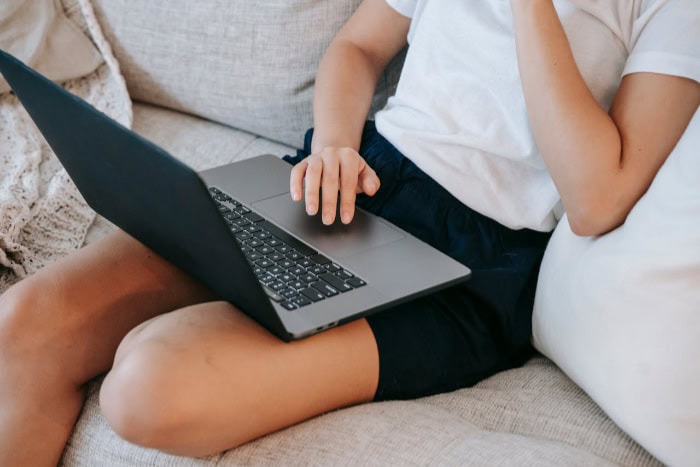 Person using laptop touchpad on couch