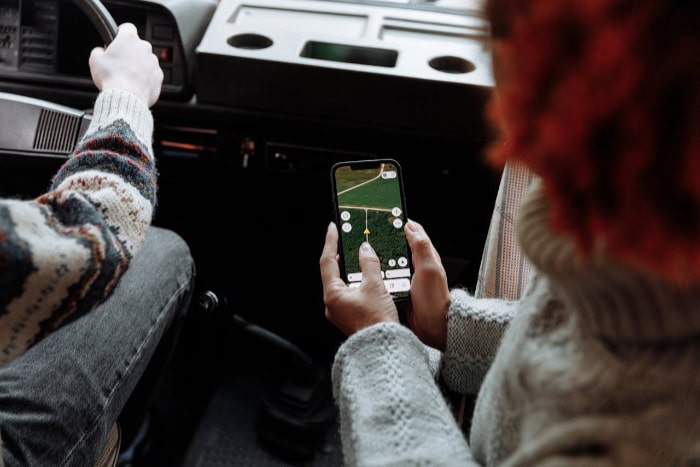 Person using smartphone GPS navigation app inside car