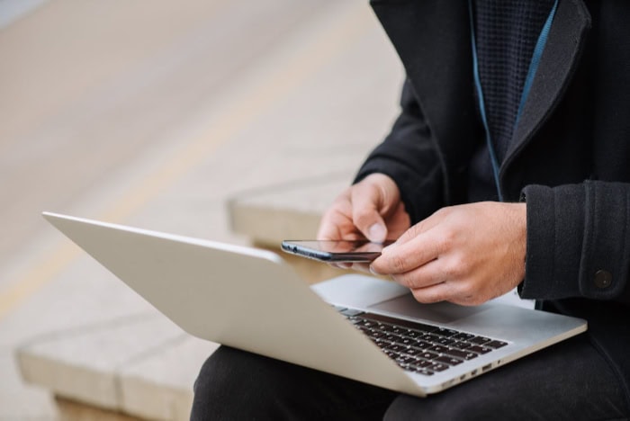 Person using smartphone and laptop outdoors