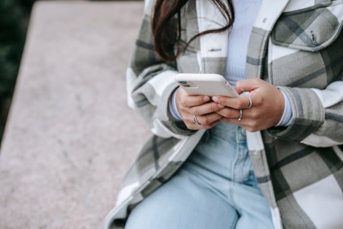 Person using smartphone while wearing plaid jacket