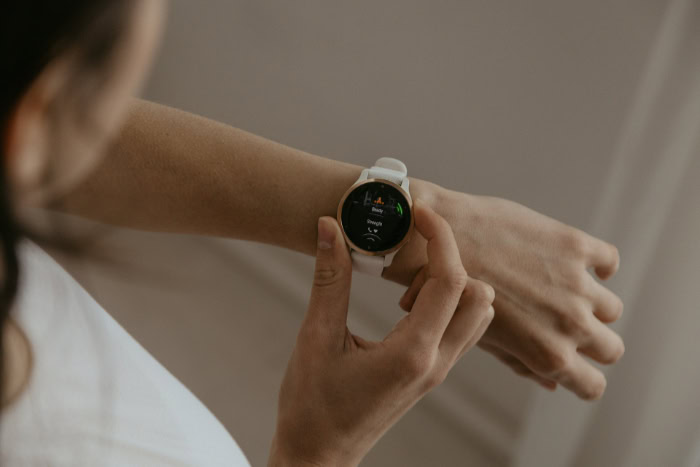 Person using white and gold smartwatch fitness tracker