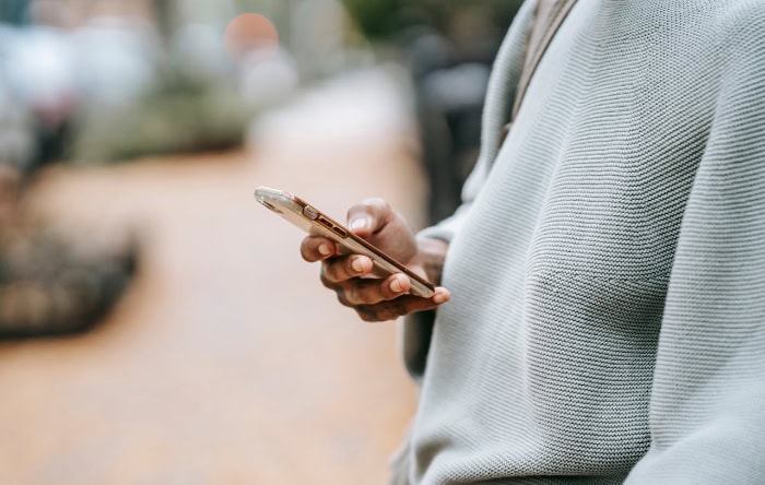 Person wearing gray sweater holding smartphone